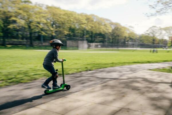 Kind mit Roller auf Gehweg