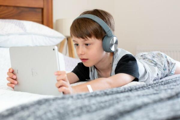 Boy with tablet on bed